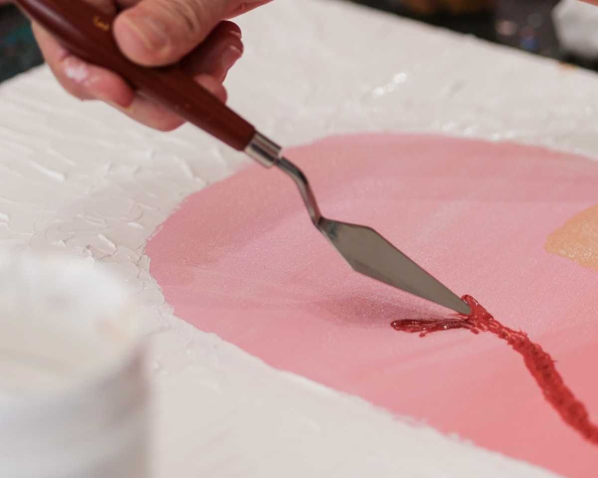 a person using a trowel to add textured paint to their Pinot & Picasso artwork