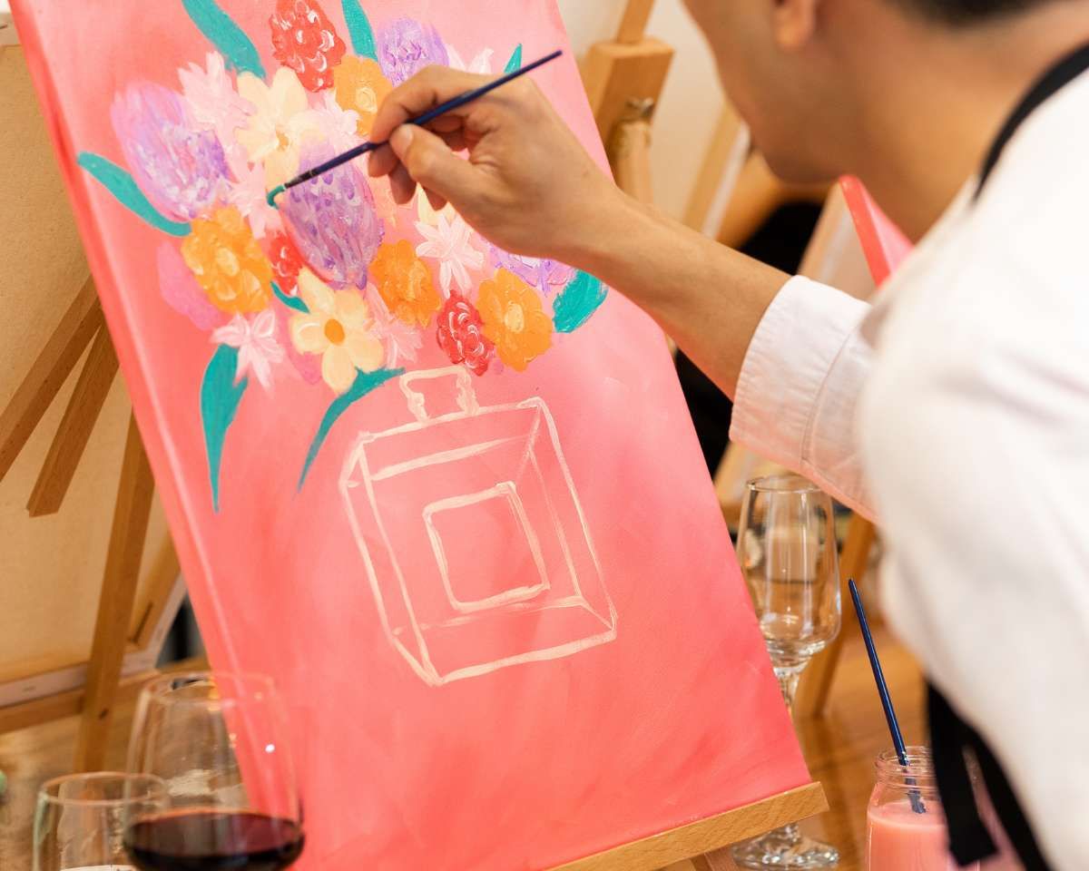 a person painting flowers onto a canvas at Pinot & Picasso