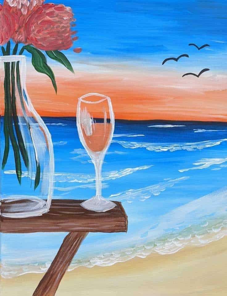Pinot & Picasso Rose Getaway has one glass of rose and a vase of flowers overlooking the seaside